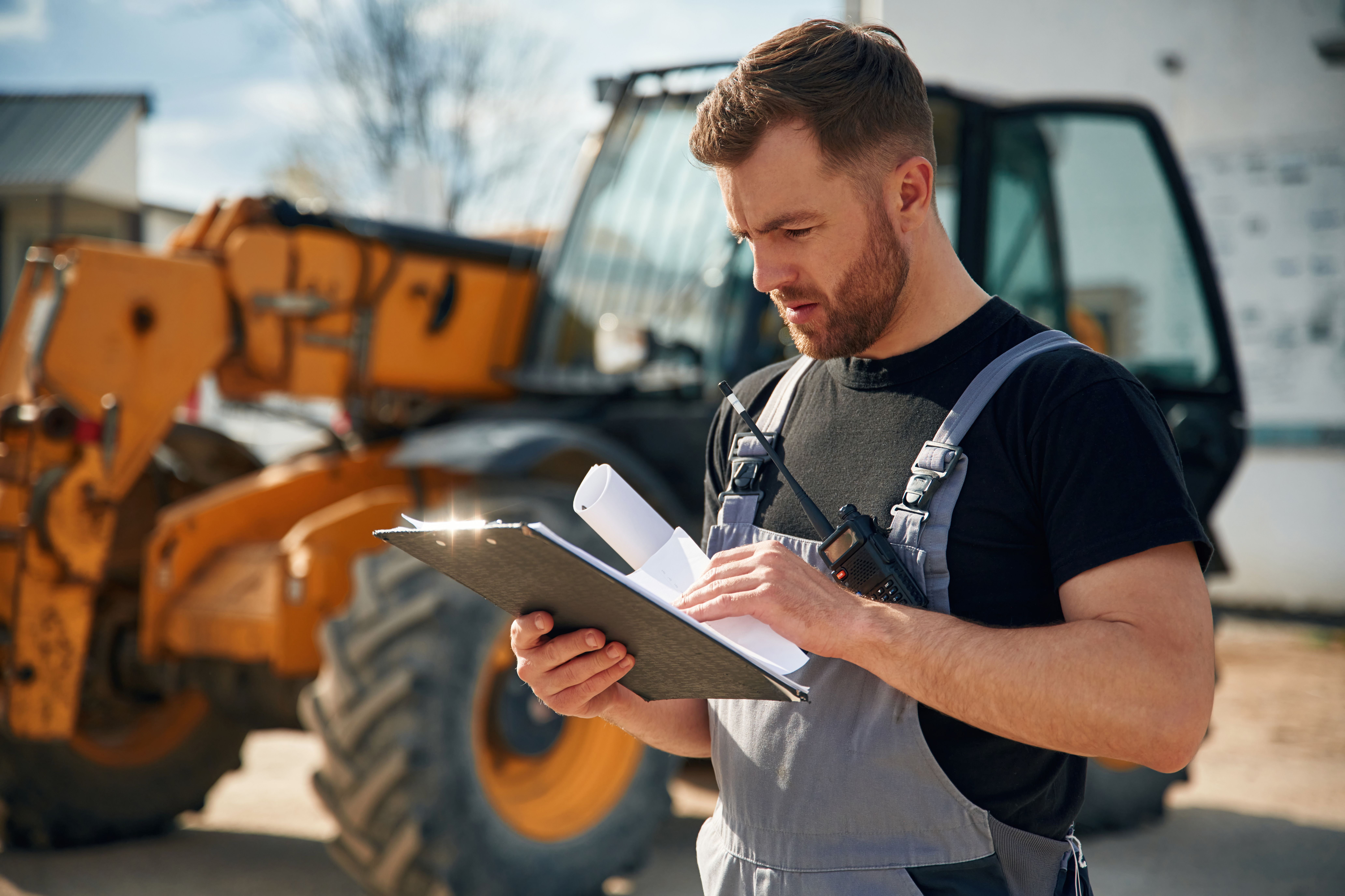 Data in the notepad, reading. Man is with tractor. Agricultural worker.